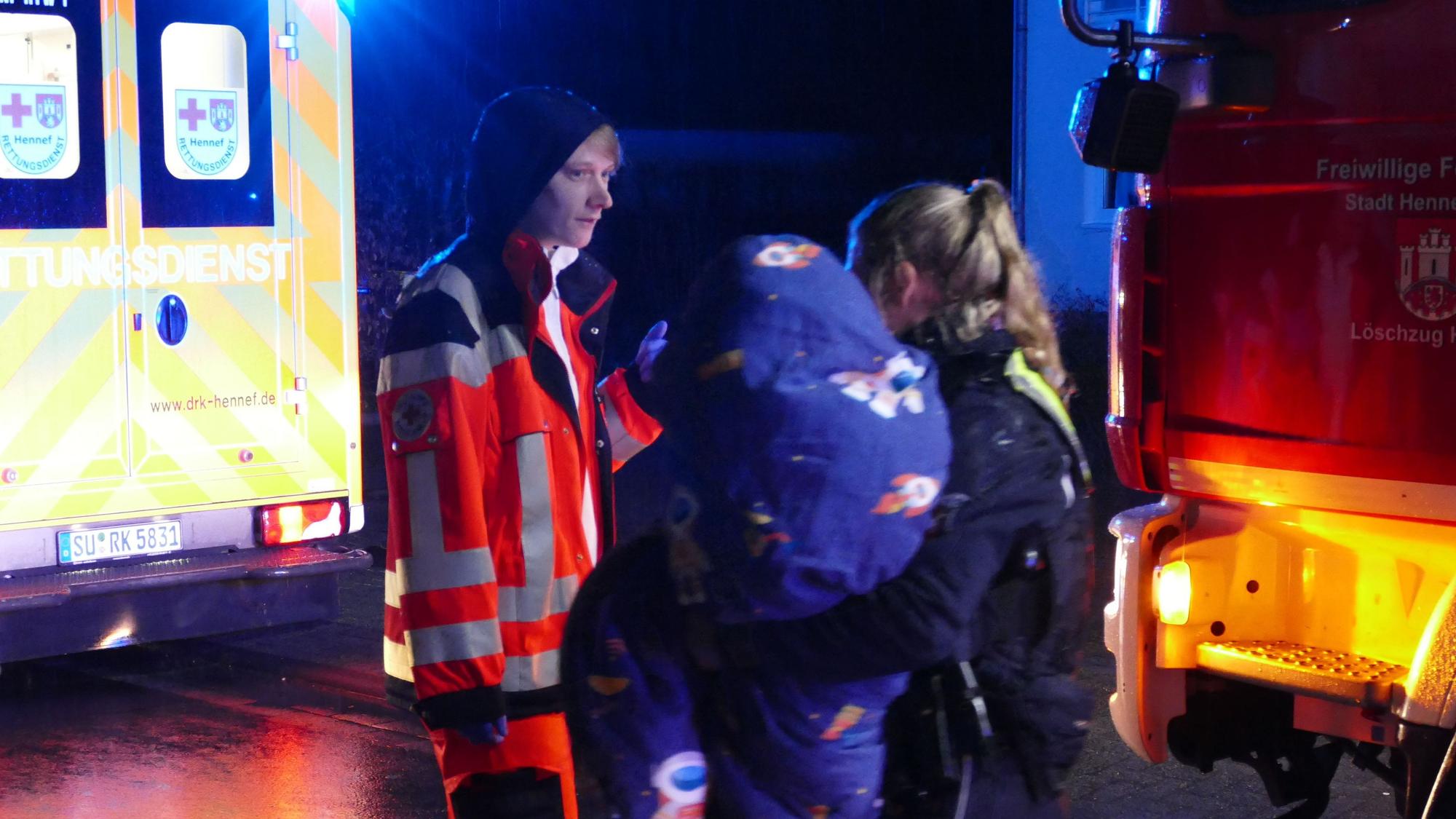 Eine Polizistin hält ein in eine Decke gewickeltes Kind auf dem Arm.