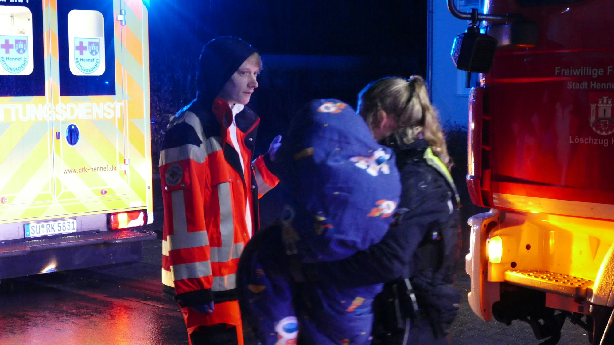 Eine Polizistin hält ein in eine Decke gewickeltes Kind auf dem Arm.