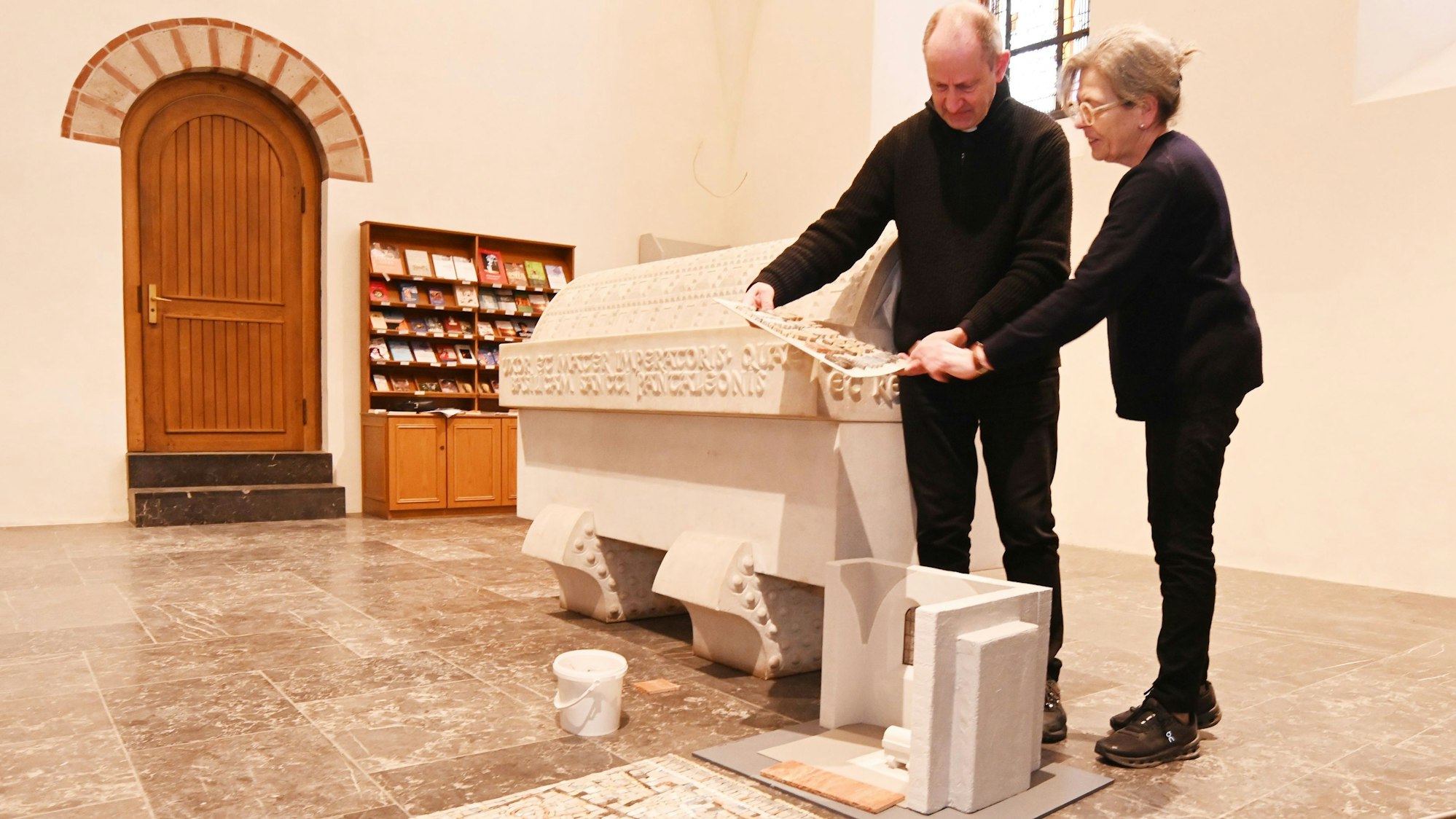Pfarrer Dr. Volker Hildebrandt und Künstlerin Maria Fernández Oriz stehen vor einem Sarkopharg.