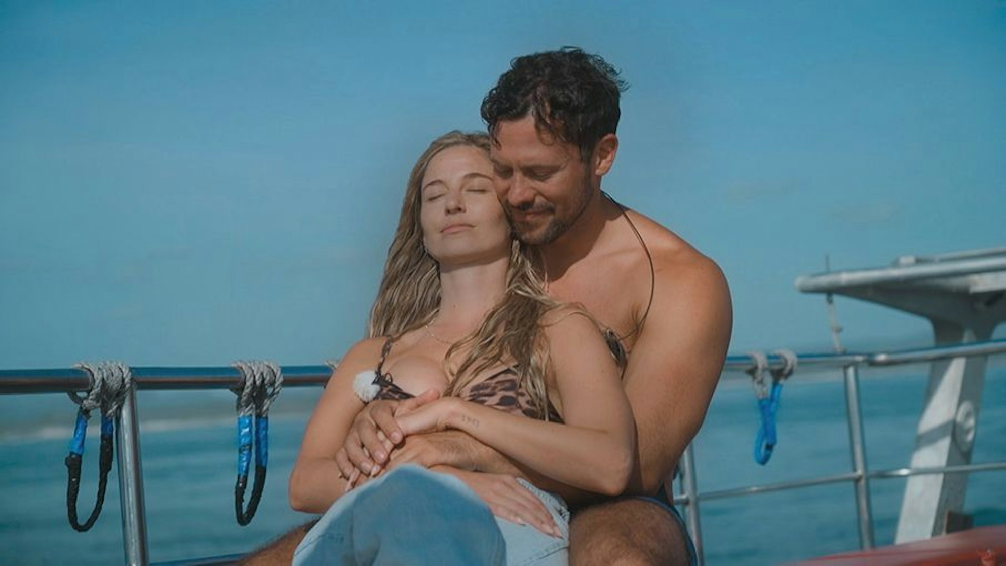 Ein Mann hält eine Frau im Bikini im Arm.