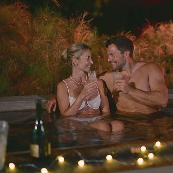Eine Frau und ein Mann sitzen im Pool nebeneinander und lächeln sich an.