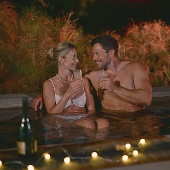 Eine Frau und ein Mann sitzen im Pool nebeneinander und lächeln sich an.