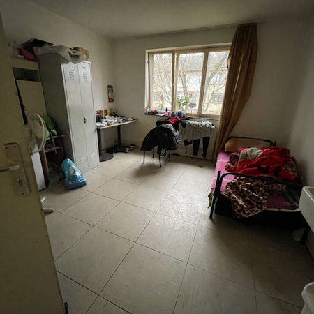 Zu sehen ist ein Raum, in dem sich ein Spind, ein Bett und ein Wäscheständer befinden.