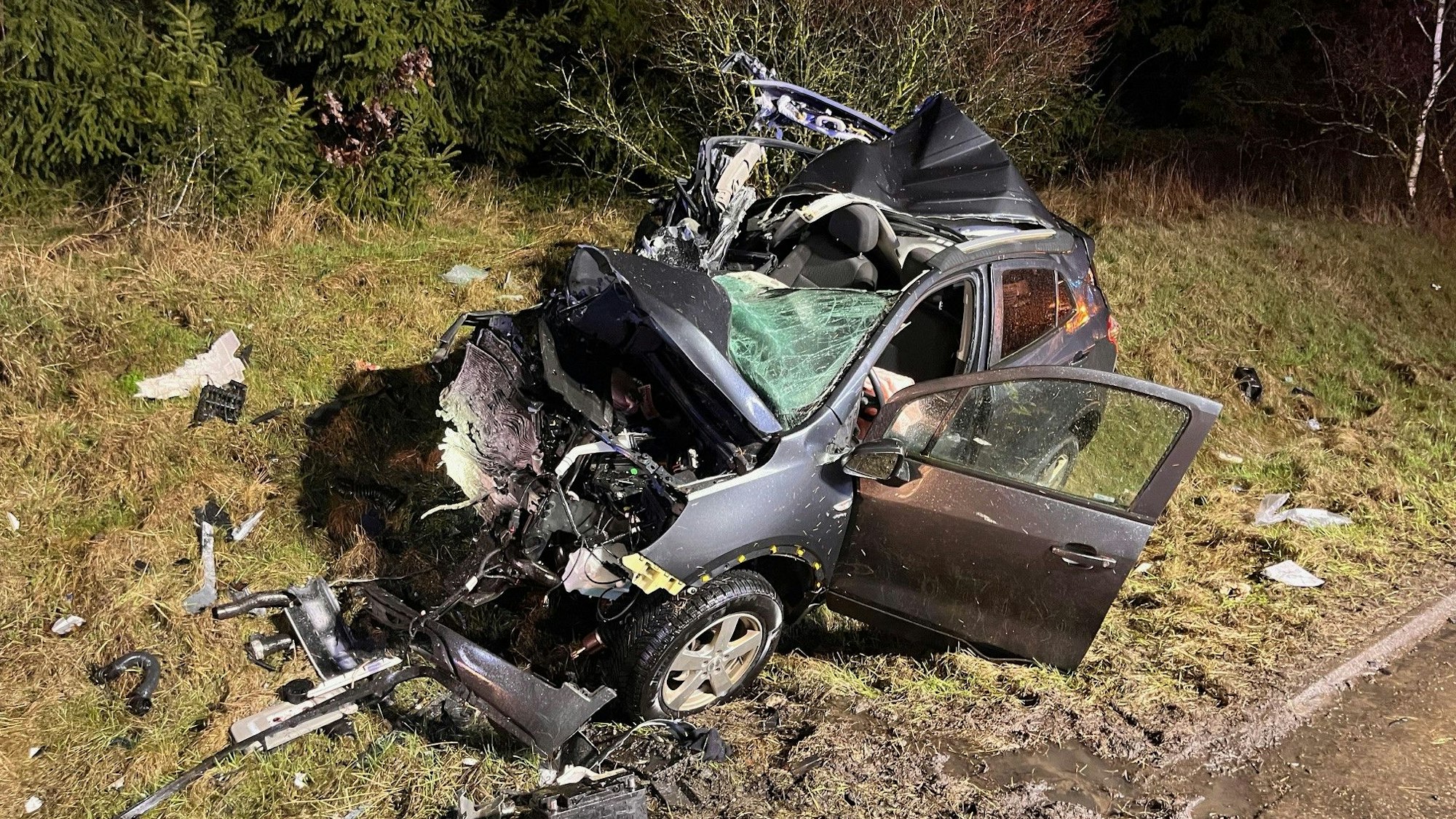 Ein stark beschädigtes Auto liegt im Straßengraben neben einer Straße.