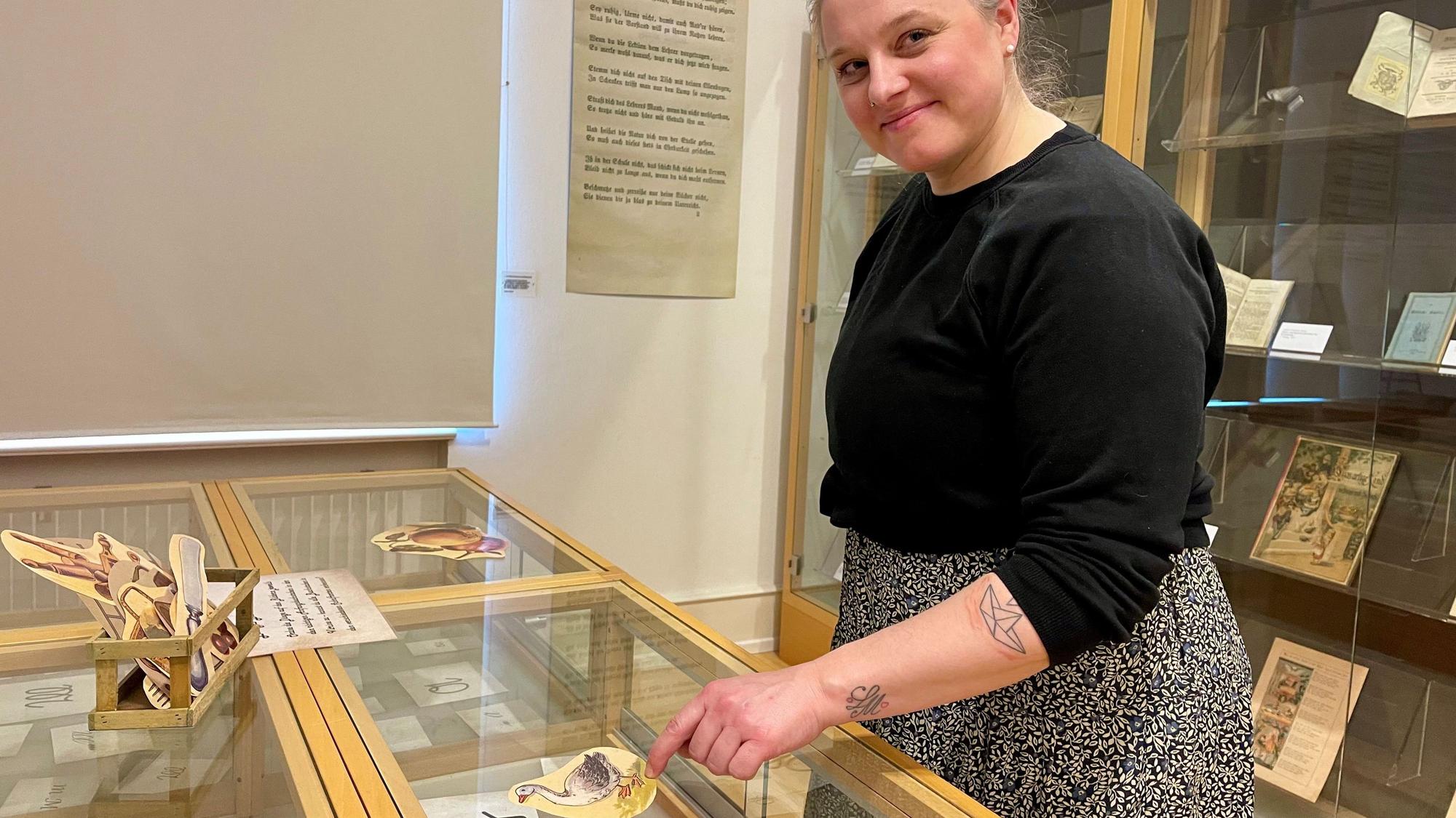 Eine Frau steht an einer Vitrine mit Buchstaben auf Papier.