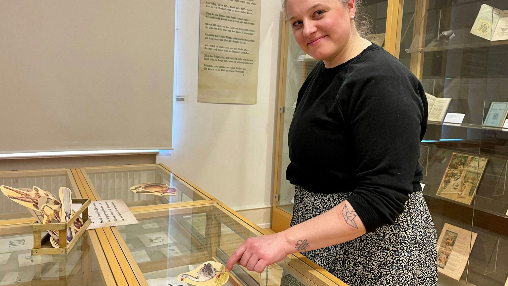 Eine Frau steht an einer Vitrine mit Buchstaben auf Papier.