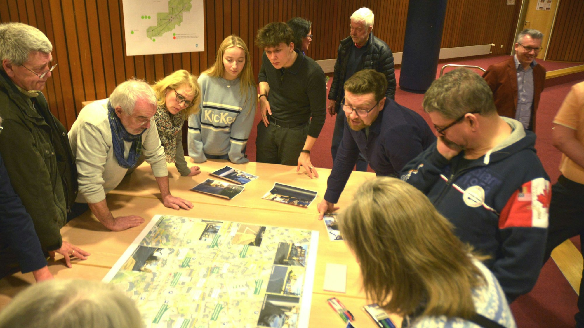 Mehrere Leute stehen um einen Stadtplan herum, der auf einem Tisch liegt.