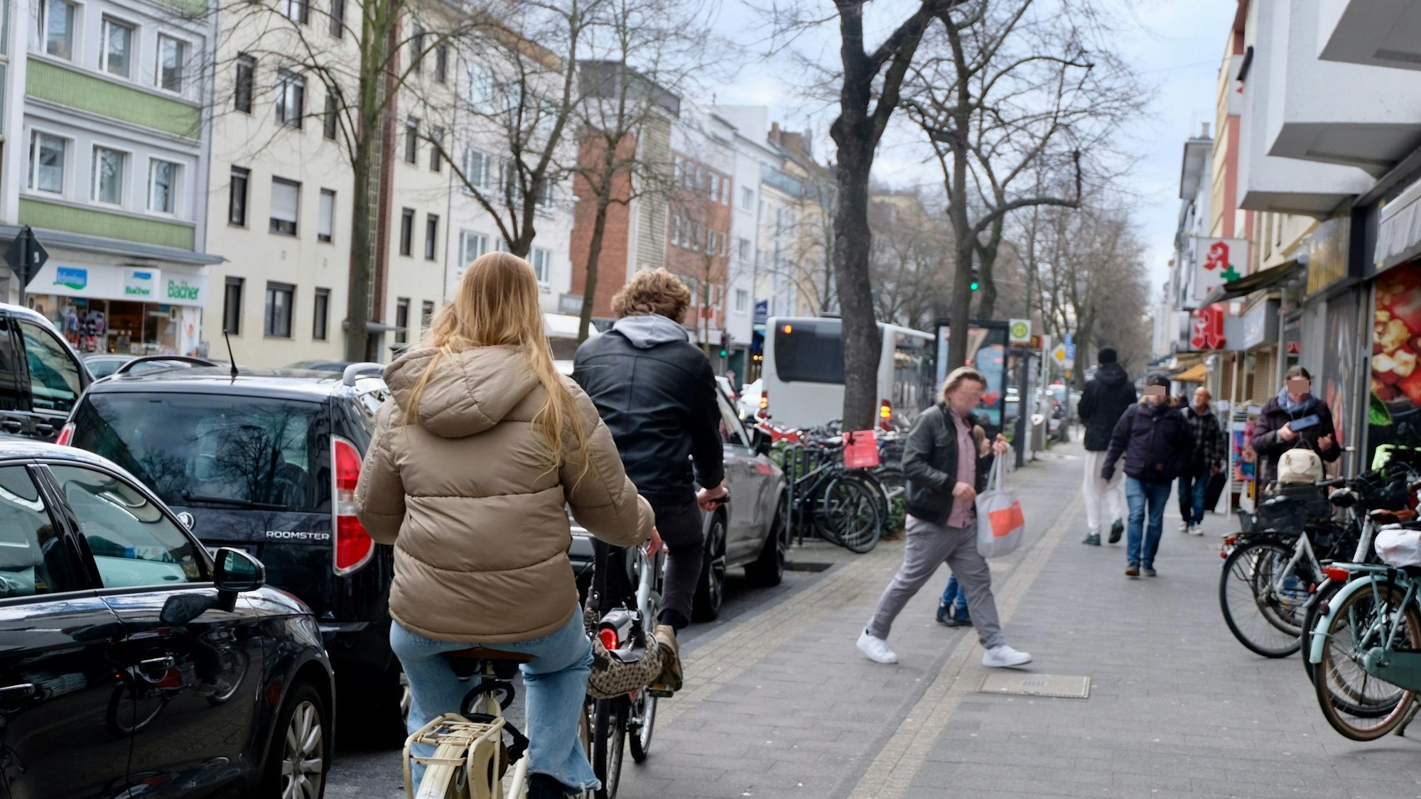 Radfahrer fahren auf dem Radstreifen, Fußgänger sind auf dem direkt daneben liegenden Gehweg unterwegs.