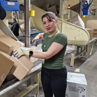 UPS Air Hub. Logistikzentrum mit Sortieranlage am Flughafen Köln/Bonn. Mitarbeiterin Diman Najmaldin nimmt die Pakete aus der Wendelrutsche und stapelt sie in einen Container.