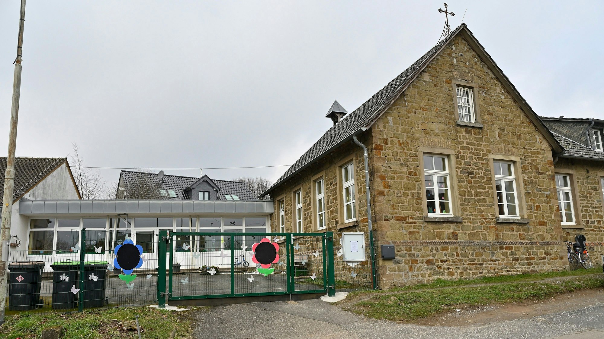 Ein altes Naturstein-Haus mit einem modernen Kindergartenanbau.