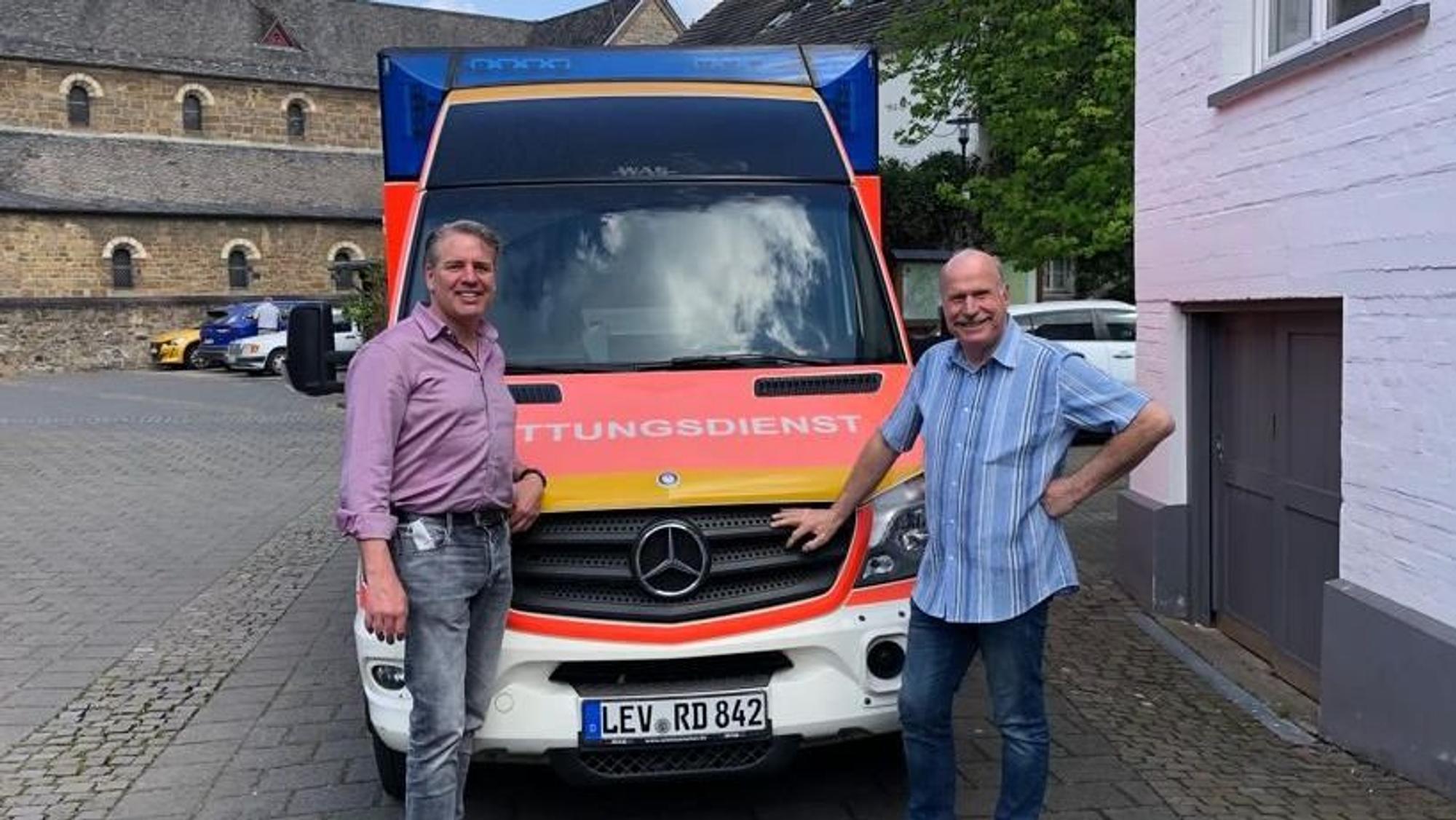 Odenthals Bürgermeister Robert Lennerts (links) und Gerd Kortschlag (Awo) stehen vor einem Rettungswagen in Odenthal.