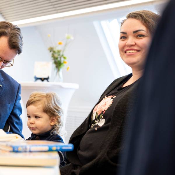 Hendrik Wüst (CDU), Ministerpräsident von Nordrhein-Westfalen, spielt am Tisch mit seinem Ehrenpatenkind Daniel, rechts Mutter Anna Marchenko.