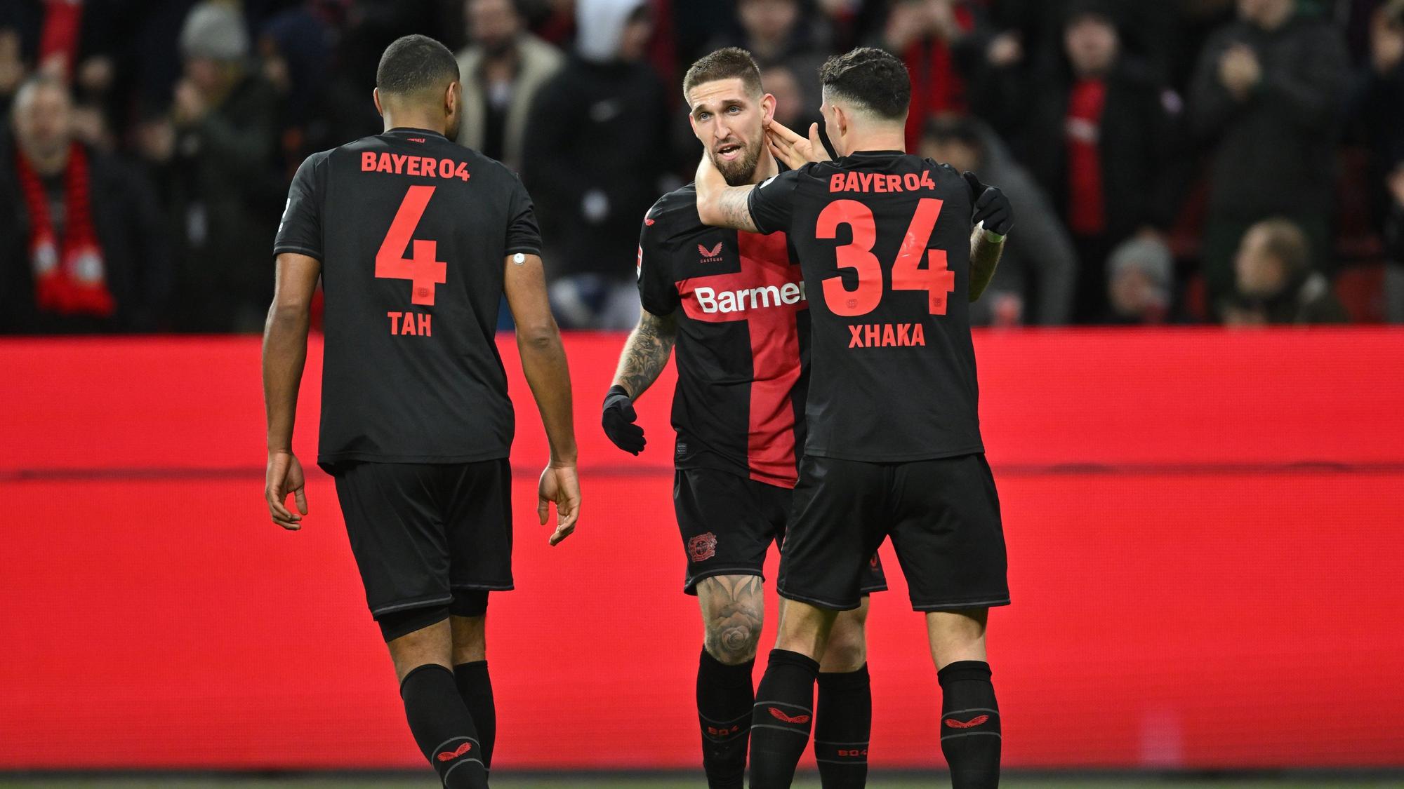 23.02.2024, Nordrhein-Westfalen, Leverkusen: Fußball: Bundesliga, Bayer Leverkusen - FSV Mainz 05, 23. Spieltag in der BayArena, Leverkusens Torschütze Robert Andrich (M) jubelt mit Jonathan Tah (l) und Granit Xhaka über das Tor zum 2:1. WICHTIGER HINWEIS: Gemäß den Vorgaben der DFL Deutsche Fußball Liga bzw. des DFB Deutscher Fußball-Bund ist es untersagt, in dem Stadion und/oder vom Spiel angefertigte Fotoaufnahmen in Form von Sequenzbildern und/oder videoähnlichen Fotostrecken zu verwerten bzw. verwerten zu lassen. Foto: Marius Becker/dpa +++ dpa-Bildfunk +++