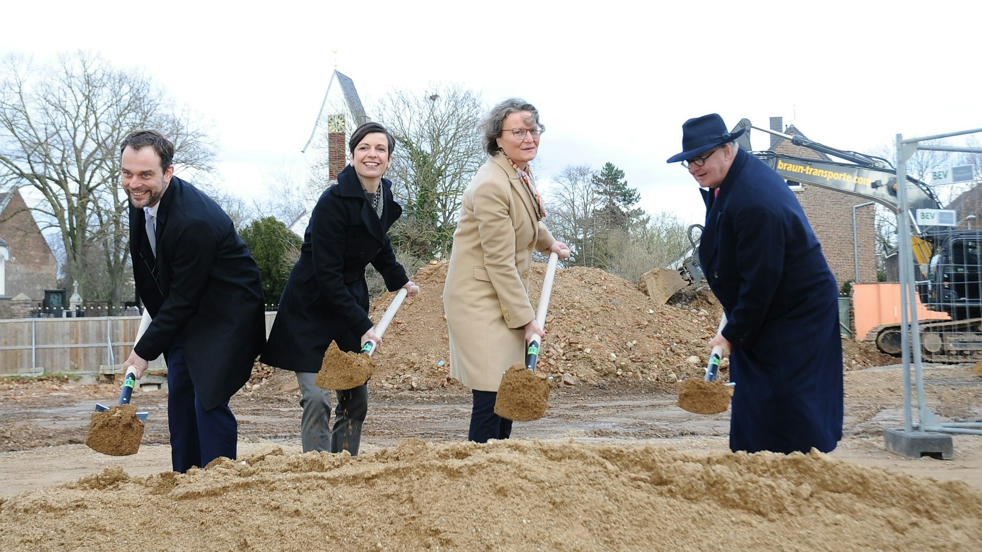 Männer und Frauen setzen einen Spatenstich.