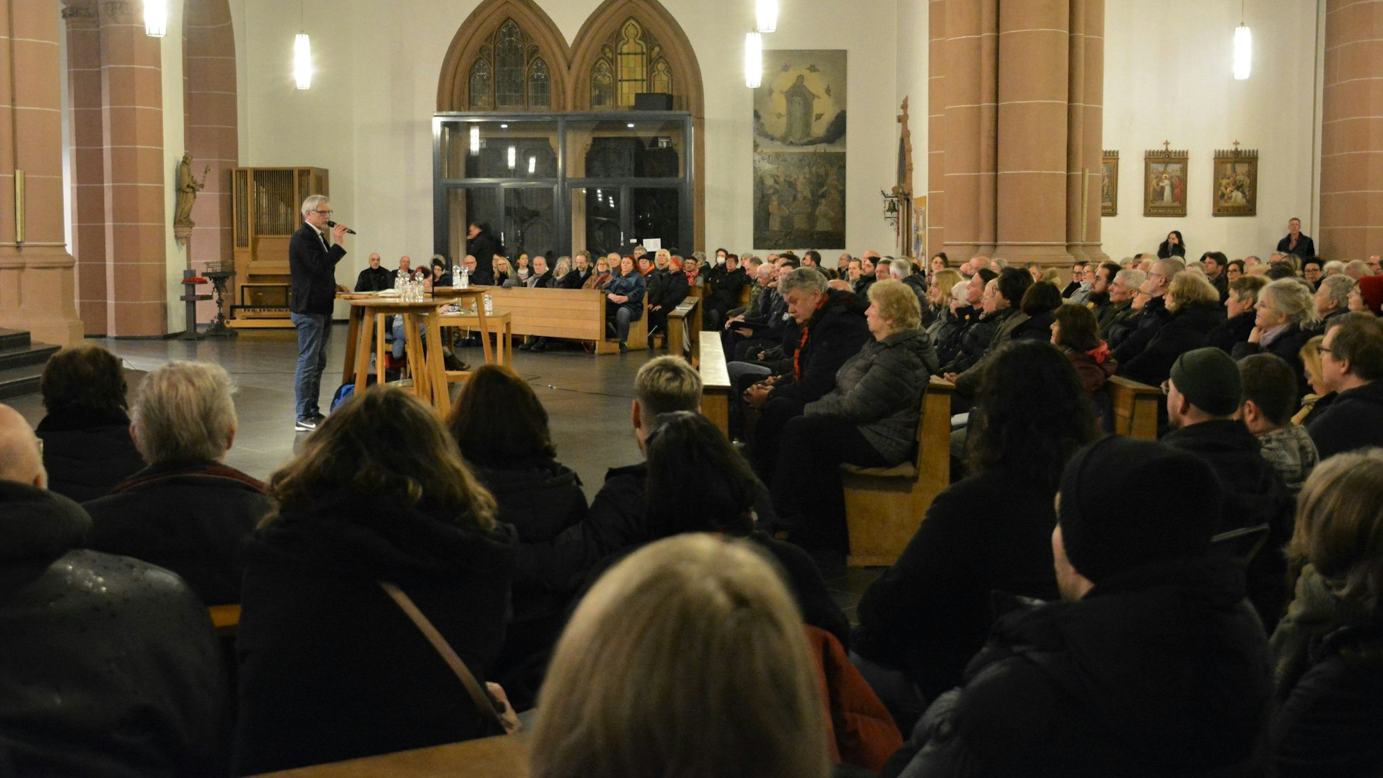 Andreas Hupke spricht in ein Mikrofon vor vollbesetzten Kirchenbänken.