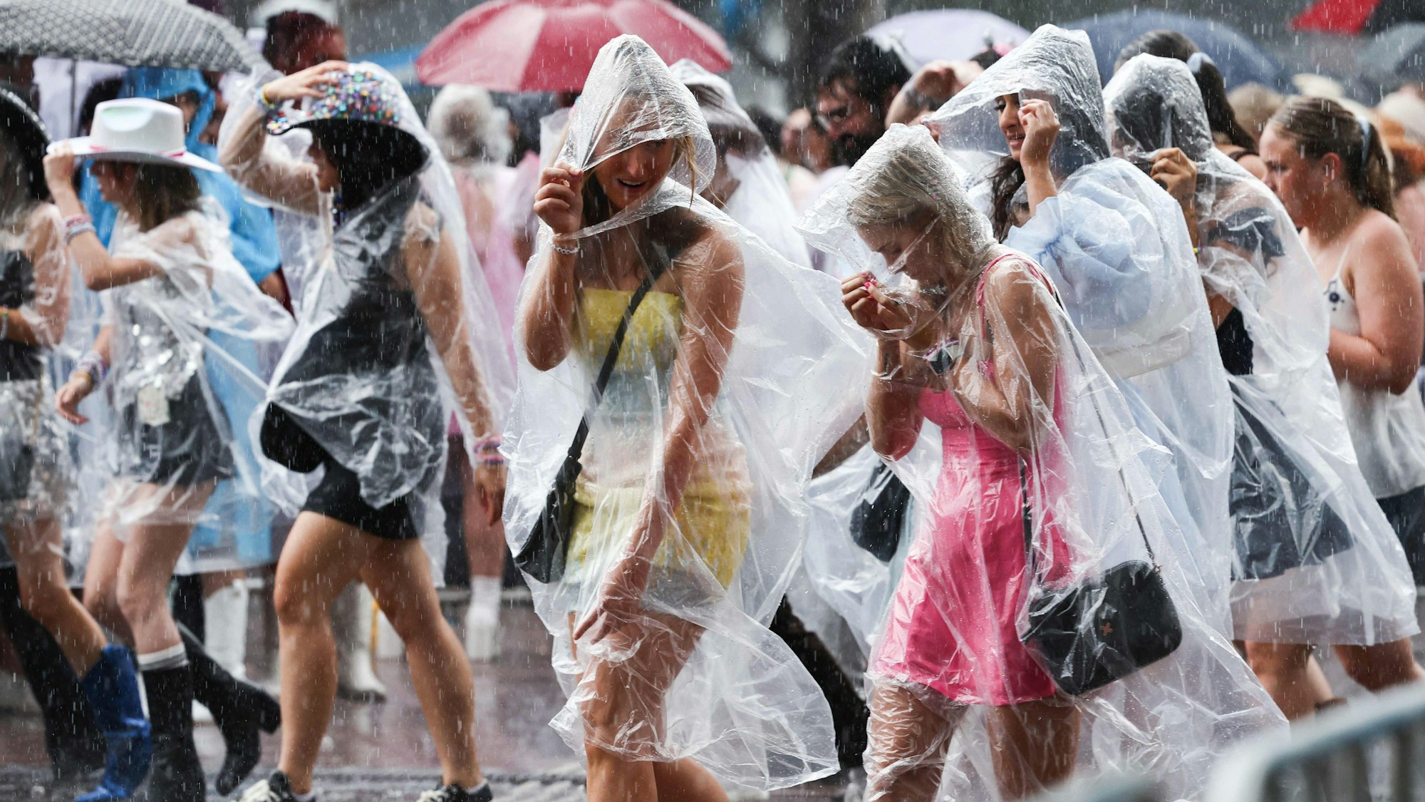 TOPSHOT - Fans of US singer Taylor Swift, also known as a Swifties, shelter from the rain as they arrive for Swift's concert in Sydney on February 23, 2024. (Photo by DAVID GRAY / AFP)