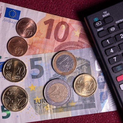 ARCHIV - 17.11.2023, Mecklenburg-Vorpommern, Schwerin: Die Summe von 18,94 Euro liegt auf einem Tisch neben der Fernbedienung für einen Fernseher.