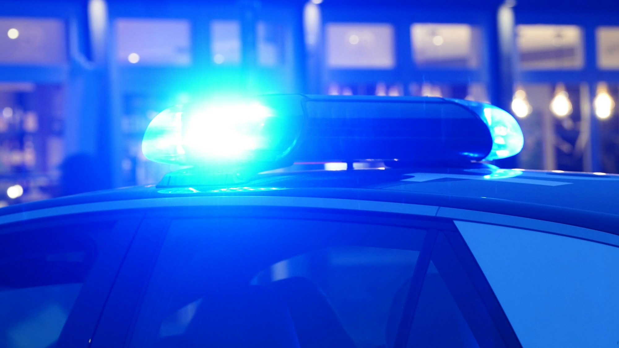 Ein Blaulicht leuchtet auf dem Dach eines Polizeiautos während einer Polizeiabsperrung.