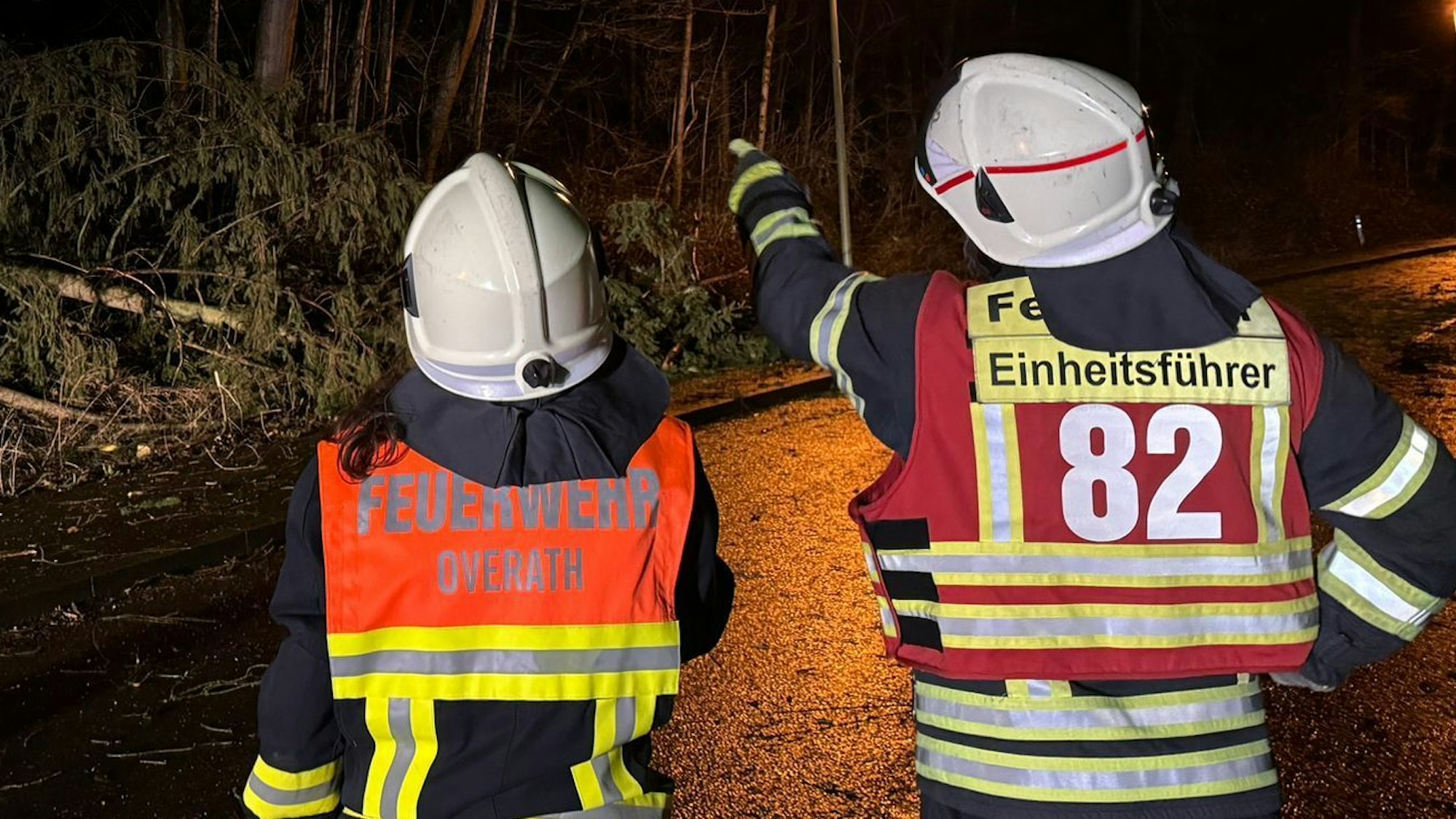 Ein Einheitsführer der Feuerwehr Overath zeigt einer Feuerwehrfrau, was an der Einsatzstelle zu tun ist.