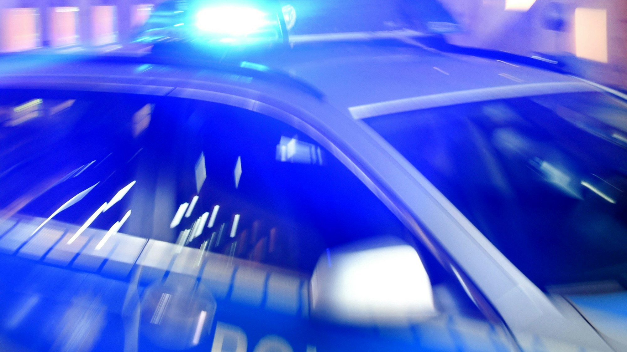Ein Streifenwagen der Polizei steht mit eingeschaltetem Blaulicht auf der Straße.