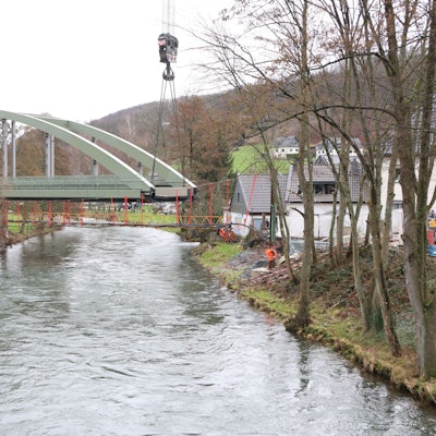 Eine Stahlbrücke mit Bogen über einem Fluss.