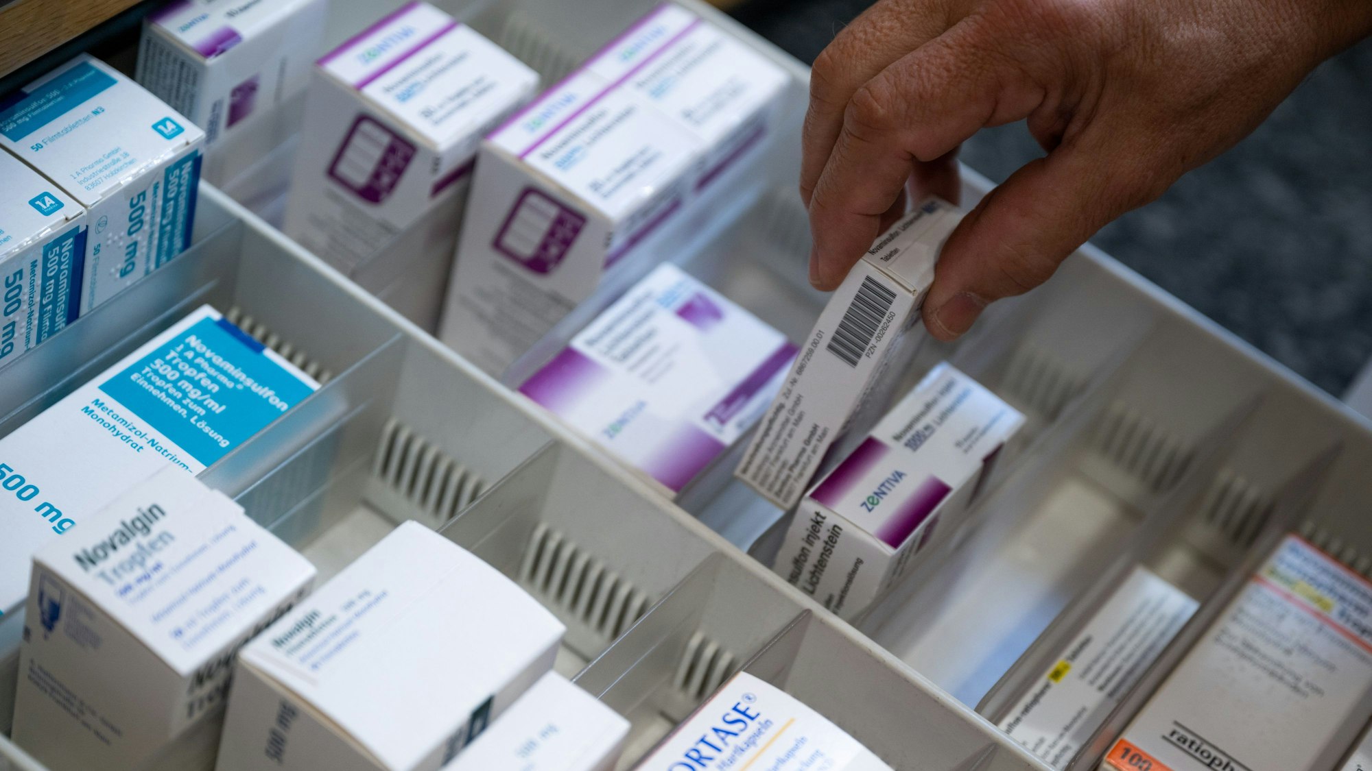Ein Apotheker holt eine Medikamentenverpackung aus einer Schublade in einer Apotheke.