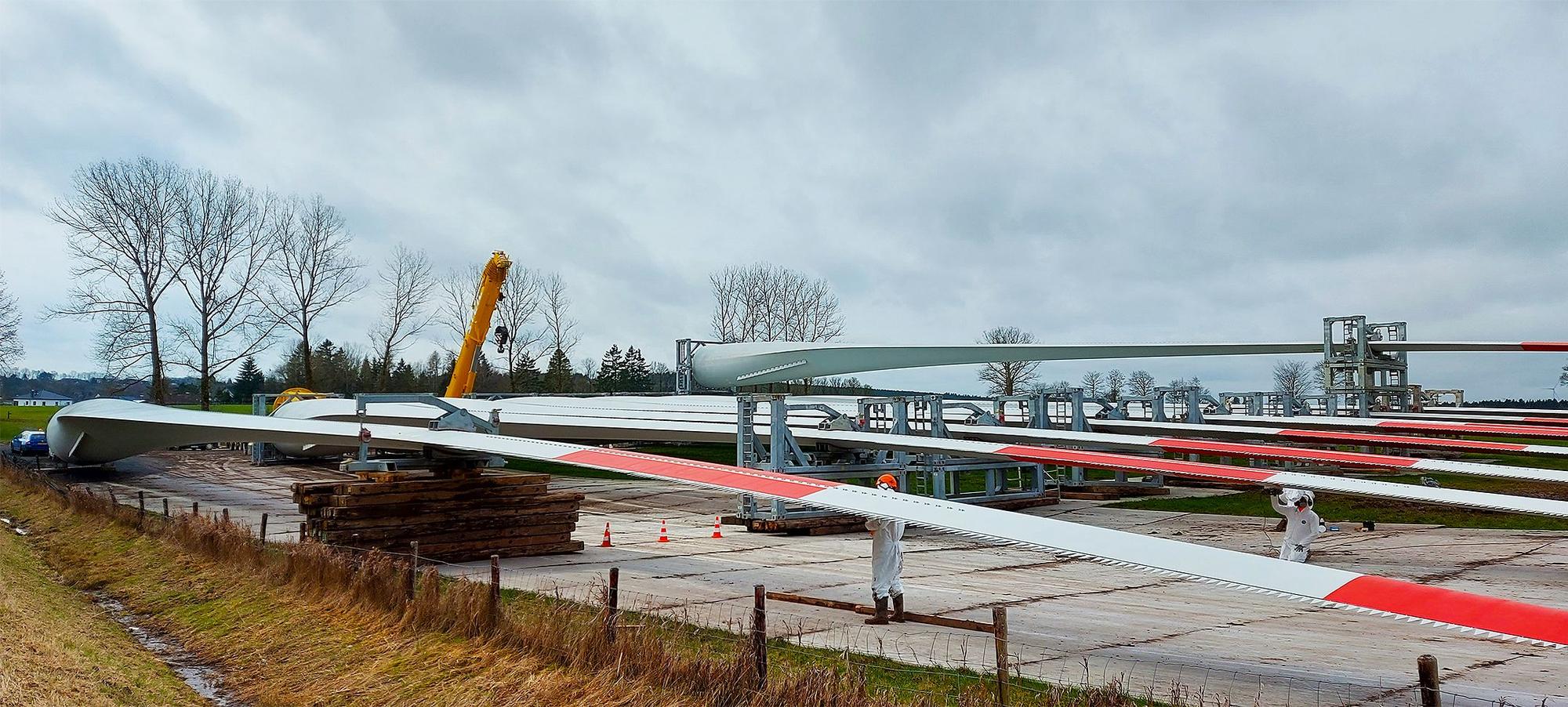 Rotorblätter lagern auf einer Wiese.