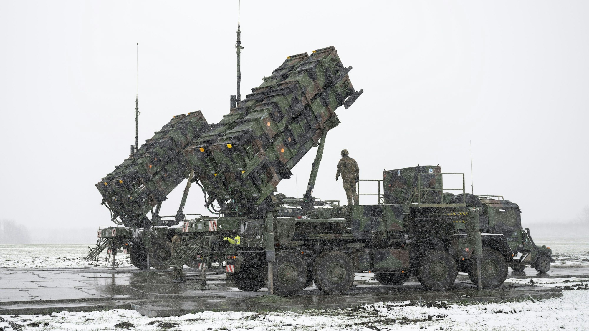 Soldaten der Bundeswehr stehen auf einem Anhänger mit Abschussrampen für Lenkflugkörper des Patriot-Luftabwehrsystems auf einem schneebedeckten Feld im Südosten Polens.