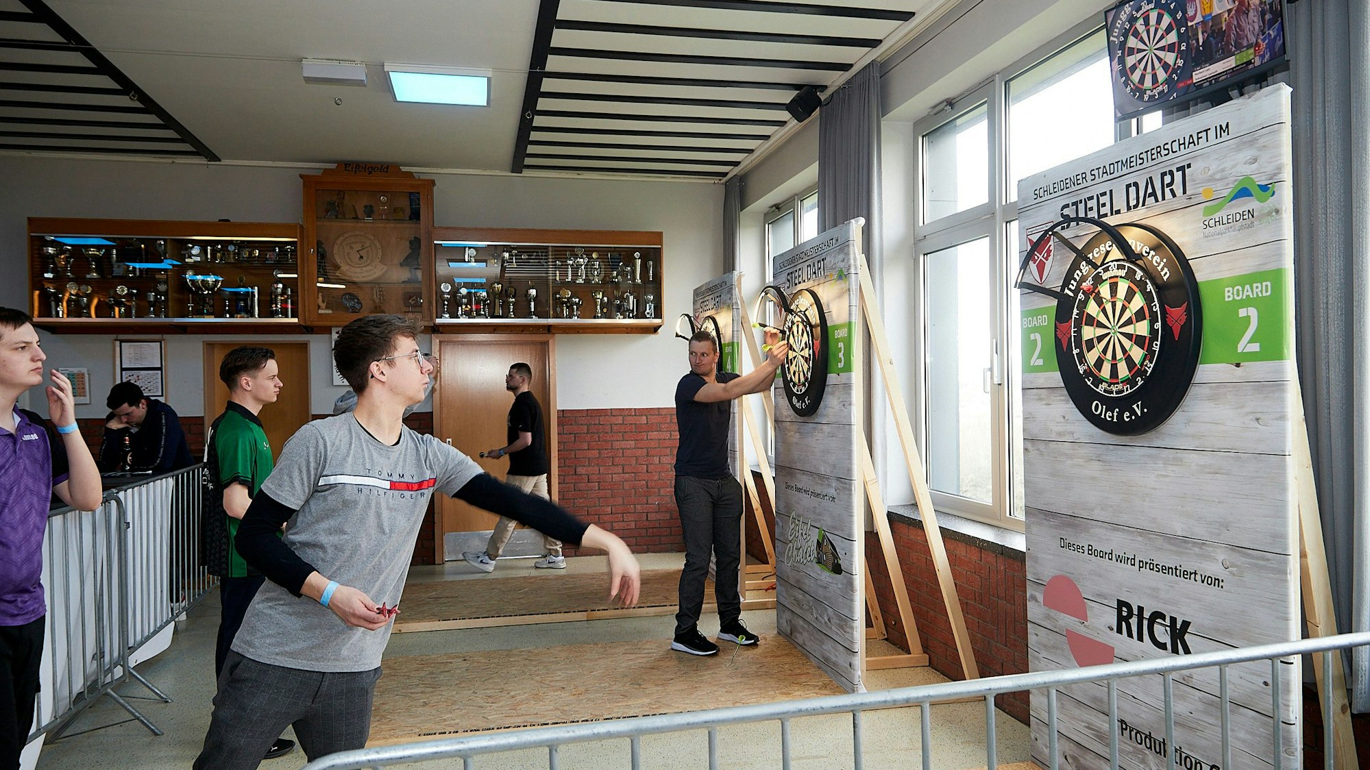 Ein junger Mann wirft einen Pfeil in Richtung Dartscheibe.