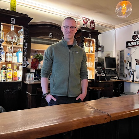 Ein Mann steht hinter der Theke in einer Kneipe.