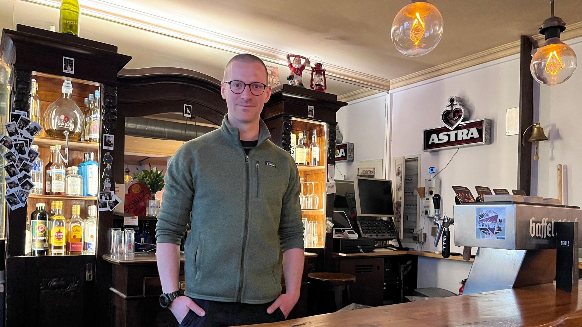 Ein Mann steht hinter der Theke in einer Kneipe.