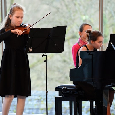 Ein Mädchen spielt Violine, ein weiteres Klavier.
