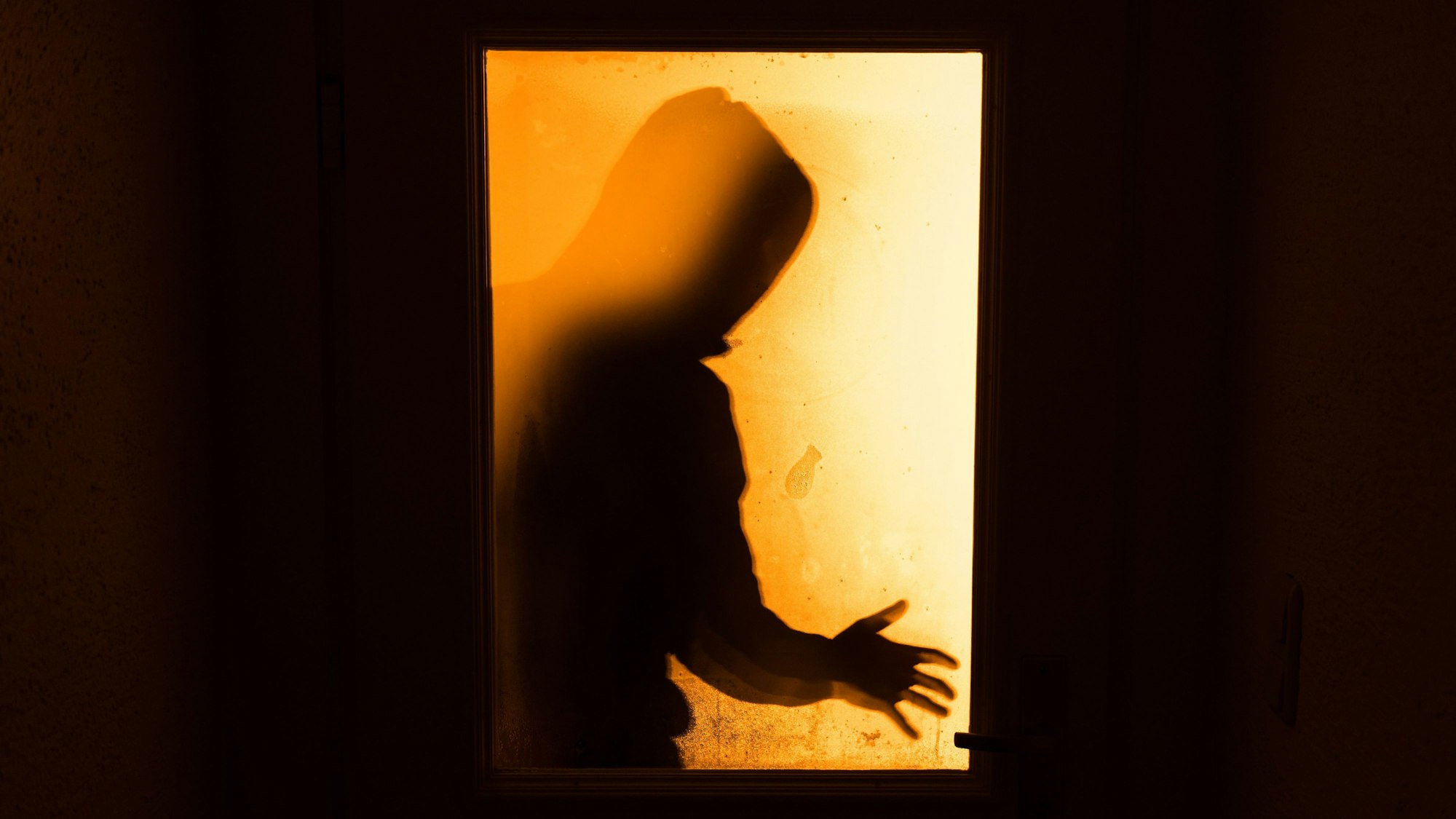 Das Bild zeigt eine Person hinter einer Glasscheibe.