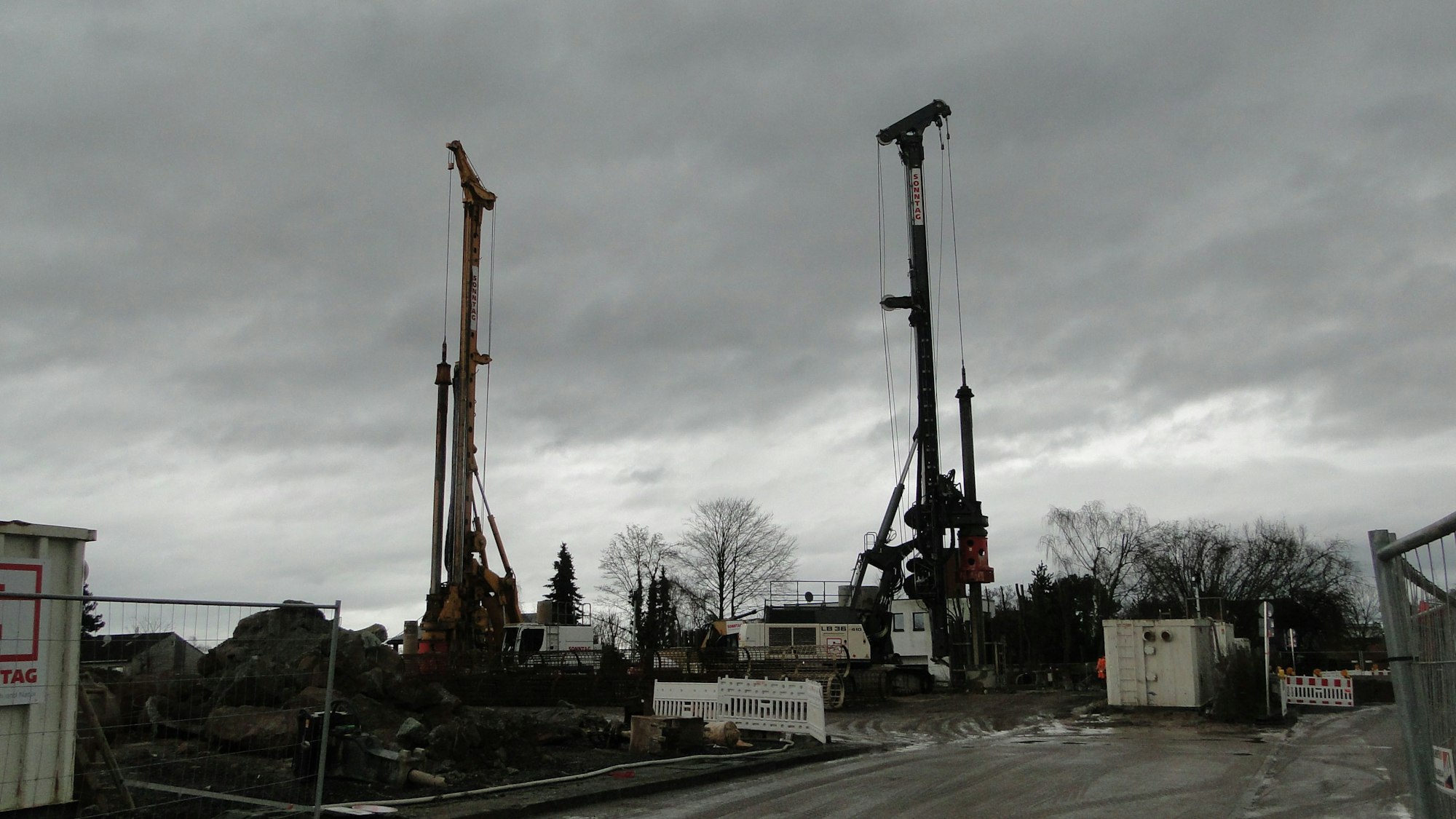 Zwei Pfahlbaumaschinen stehen auf einer Baustelle.