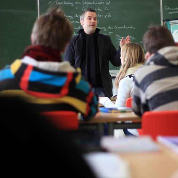 Ein Lehrer unterrichtet eine Schulklasse vor einer Tafel.