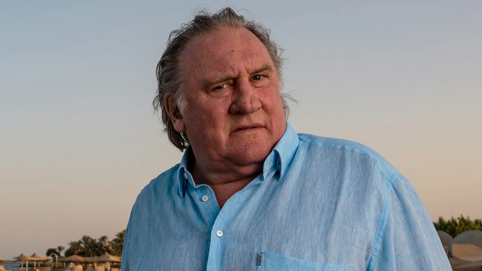 Filmstar Gérard Depardieu steht in einem blauen Hemd an einem Strand. (Archivbild)