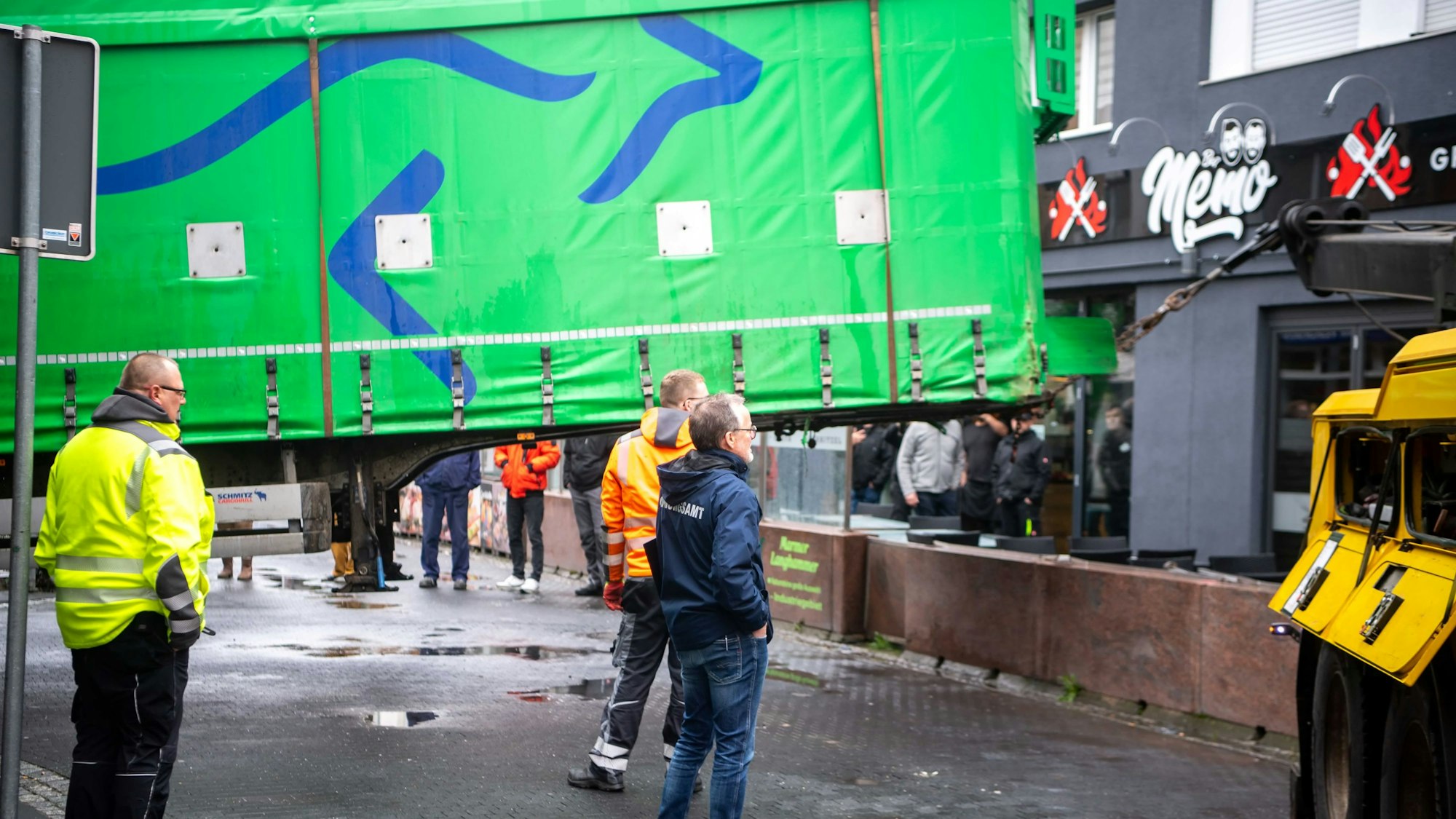 Das Bild zeigt, wie der Auflieger von einem Krank angehoben wird. Mehrere Menschen schauen sich das Spektakel an.
