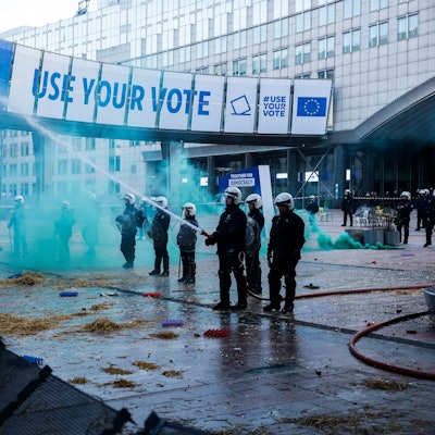 Beamte der Bereitschaftspolizei setzen einen Schlauch ein, um Brände zu löschen, die von Landwirten während einer Demonstration vor dem Europäischen Parlament gelegt wurden. (Archivbild)