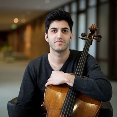Der österreichisch-iranische Cellist Kian Soltani blickt in die Kamera. Er hält sein Cello mit einem