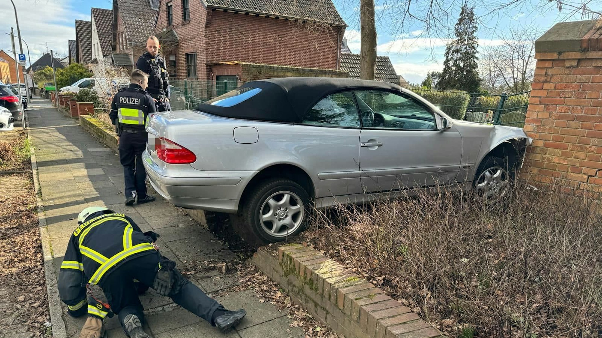 Ein silbernes Auto ist über einen Grünsteifen in eine Mauer gefahren.