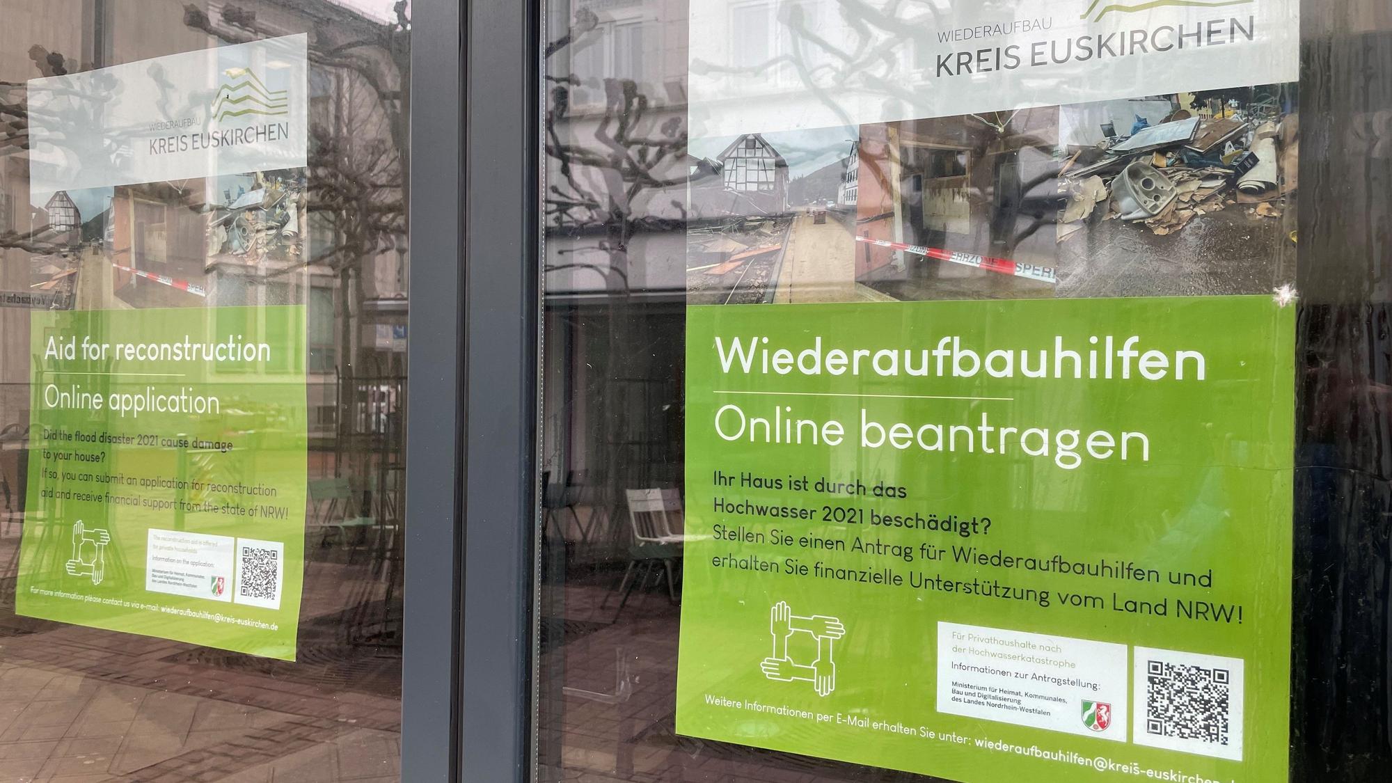Das Bild zeigt zwei Plakate in einem Geschäft in Euskirchen. Sie weisen auf die Wiederaufbauhilfe des Landes hin.