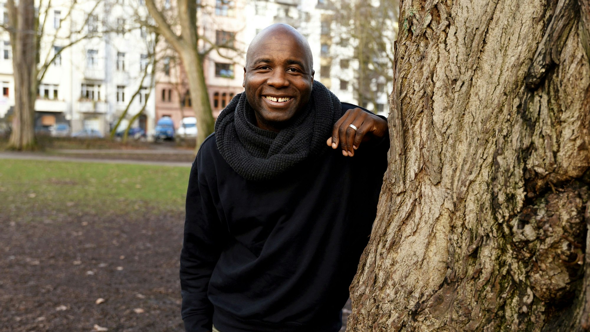 Dave Davis lehnt an einem Baum und lacht in die Kamera