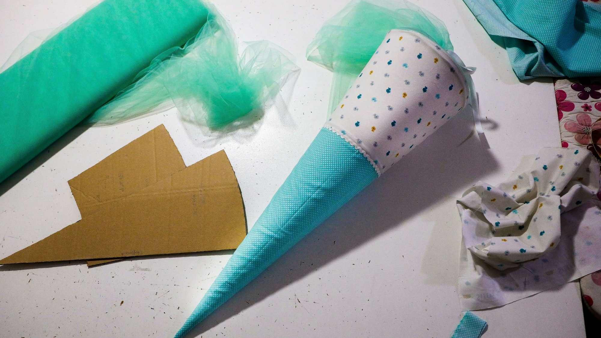 Eine Schultüte, Tüll, Stoff und zwei Papp-Rohlinge liegen der Nähwerkstatt Köln auf einem Tisch.