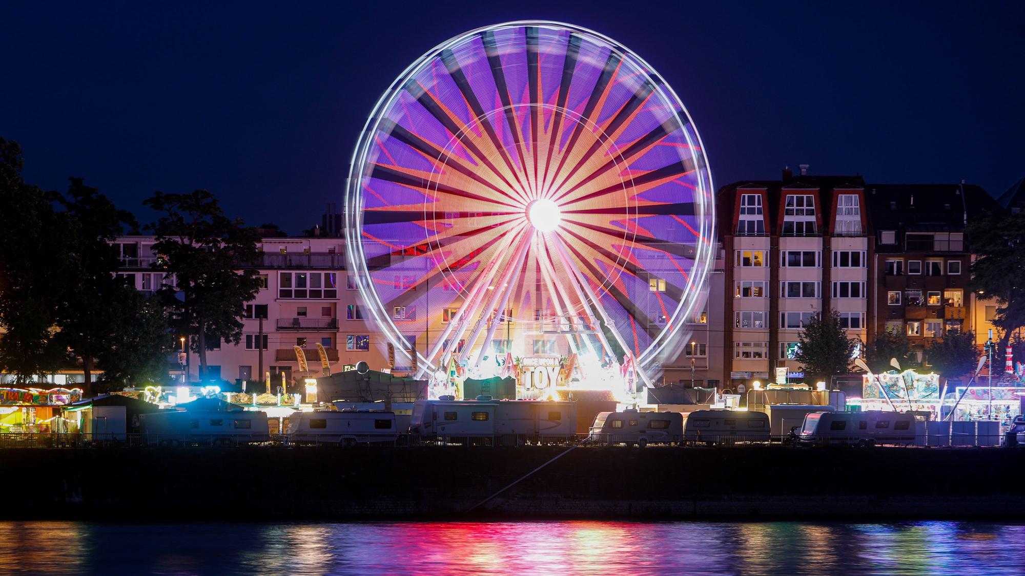 Das Europa-Riesenrad steht am Kölner Rheinufer und leuchtet lila im Dunkeln.