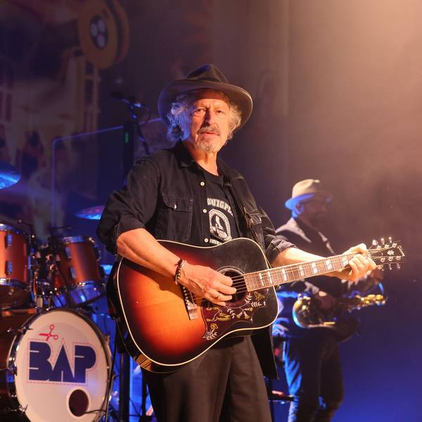 Wolfgang Niedecken steht mit Gitarre auf der Bühne.