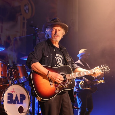 Wolfgang Niedecken steht mit Gitarre auf der Bühne.