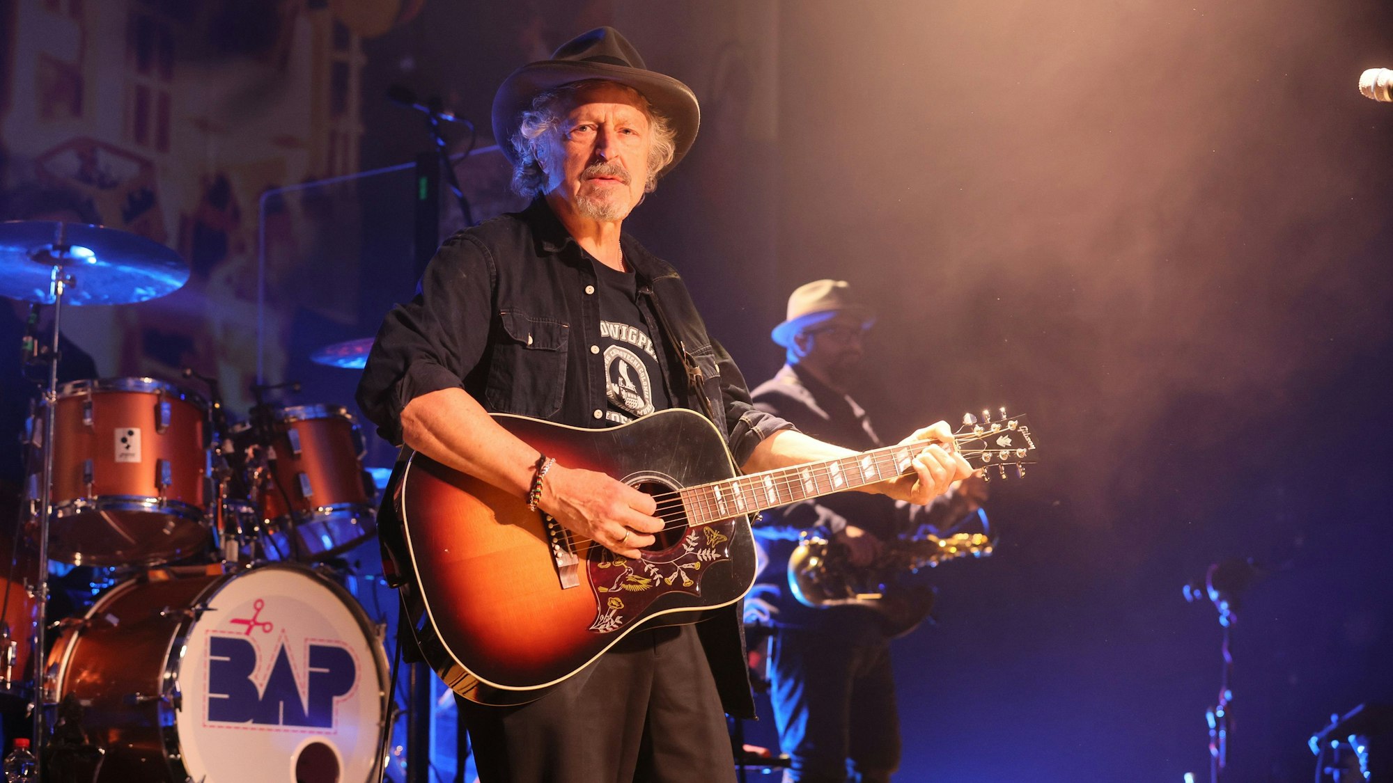 Wolfgang Niedecken steht mit Gitarre auf der Bühne.