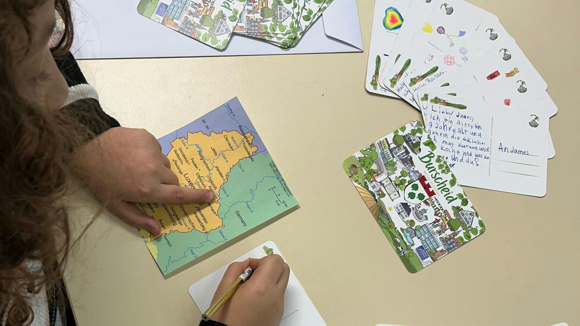 Aus Burscheid nach Bourscheid: Ein Kind schreibt eine Postkarte.