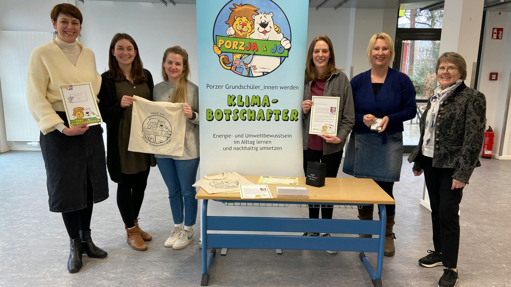 Junge und ältere Frauen stehen links und rechts von einem Aufsteller mit der Aufschrift Klimabotschafter.