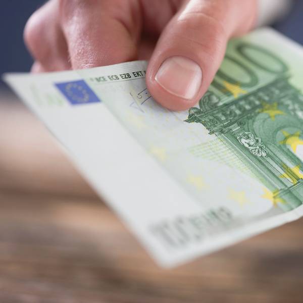 Eine Person hält einen 100-Euro-Schein in der Hand